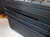 three black storage boxes stacked on top of each other on the floor