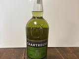 La bouteille de Chartreuse est posée sur une table en bois.