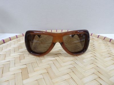 brown sunglasses on top of a woven basket on a white surface