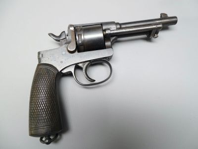Un vieux pistolet repose sur une surface blanche, avec une crosse noire