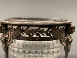 a glass bowl with a metal handle on a table