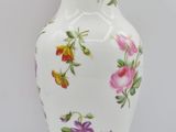 a white vase with colorful flowers on it on a white surface