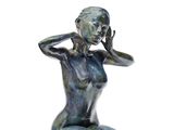 statue représentant une femme assise à genoux, les mains sur la tête