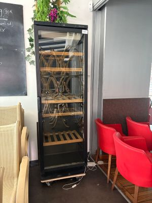 a wine cooler in the middle of a room with red chairs