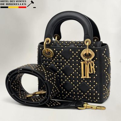 un sac à main noir avec des anses cloutées d'or et une ceinture