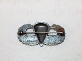 a metal pin with a heart on it on a white surface