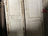 two old white doors leaning against a brick wall