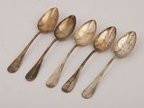 six silver spoons are lined up in a row on a white surface