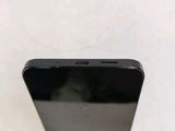 the back of a black cell phone sitting on top of a white table