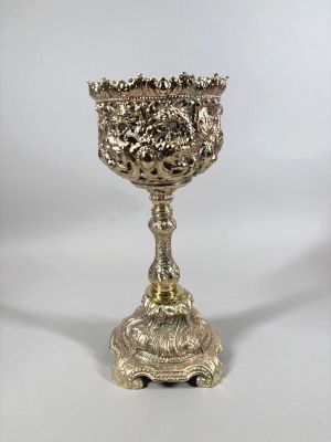 une coupe en argent ancien posée sur un socle, sur fond blanc