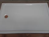 a close up of a white shower tray on top of a cardboard box