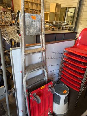 une pile de chaises rouges et une échelle dans un entrepôt