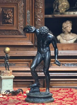 une statue représentant un homme tenant une raquette de tennis posée sur une table