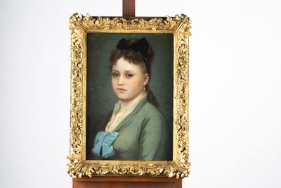 un tableau représentant une femme avec un nœud bleu, posé sur un chevalet