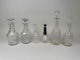 five glass bottles and a bottle stopper on a white surface