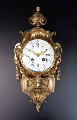 une horloge dorée accrochée au mur sur un fond noir