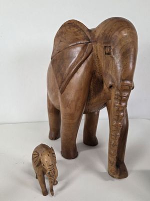 a wooden elephant and a baby elephant standing next to each other