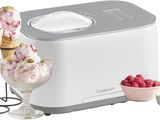 an ice cream maker with two scoops of ice cream and a bowl of raspberries