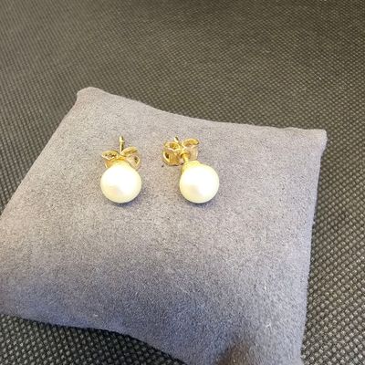 une paire de boucles d'oreilles en perles posée sur un oreiller
