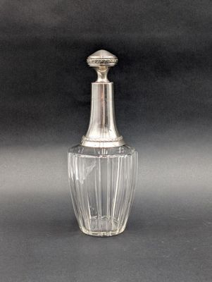 une petite bouteille en verre avec un bouchon argenté sur fond noir
