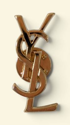 a gold ysl pin with a dollar sign on it