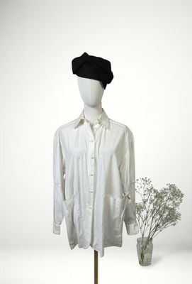 shirt on a mannequin stand with a vase of flowers in front of it