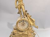 une horloge en or surmontée d'une statue d'homme