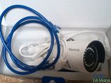 a white camera in a box with a blue cord