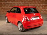 a small red car parked in front of a brick wall