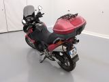 a red motorcycle parked in a room with a white wall