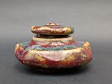a picture of a small vase with a lid on a table