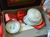 a box with plates and bowls in it on a bed