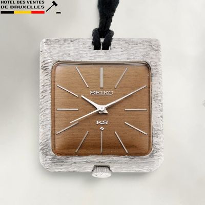 une horloge carrée argentée et marron suspendue à un cordon noir