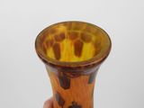 a hand holding a brown and yellow vase against a white background