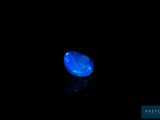 a blue diamond in the dark with a reflection on the ground