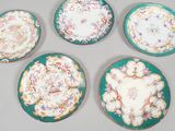 four green plates with floral designs on them on a table