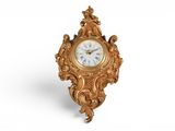 une image représentant une horloge dorée posée sur une surface blanche, sur fond blanc