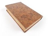 an old book with a brown cover sitting on top of a white surface