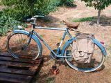 a blue bicycle that is parked next to a wooden bench