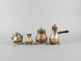 trois théières en argent et une cafetière posées sur une table