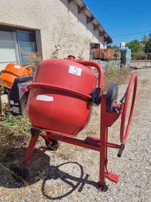 a red cement mixer sitting in front of a house