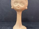 a small doll head on a table with a black background