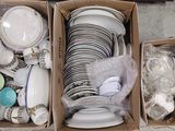 deux cartons remplis d'assiettes et de tasses posés par terre