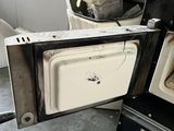 two old stoves in a dirty kitchen with a broken door
