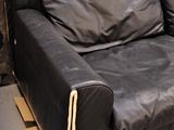 a black leather couch sitting in front of a black wall
