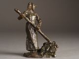 a bronze statue of a man with a cross and a dog