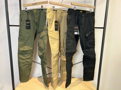 trois pantalons pour homme suspendus à un portant dans un magasin de vêtements