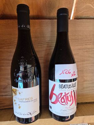 deux bouteilles de vin posées sur une étagère l'une à côté de l'autre