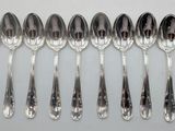 six silver spoons are lined up in a row on a white surface