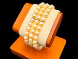 un bracelet orné de perles, posé sur un support en bois, sur fond noir